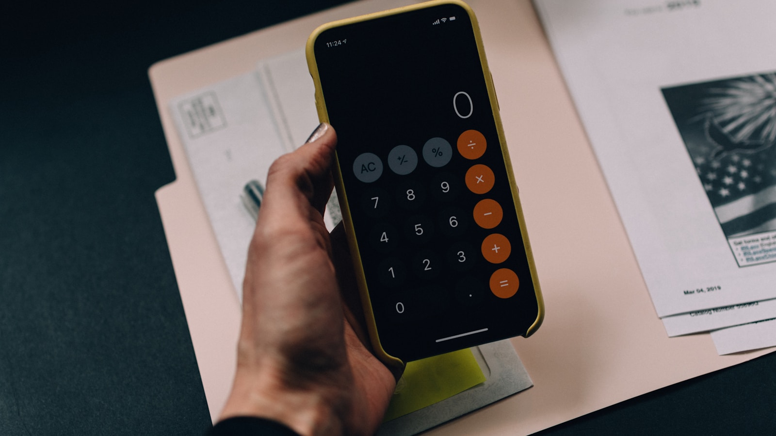 Person reviewing bills and a calculator at a kitchen table with notes