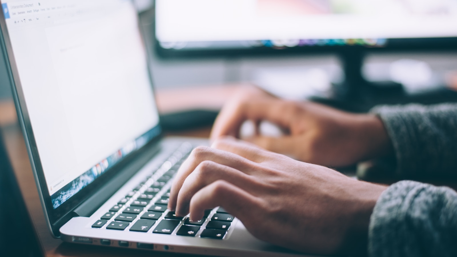 Person typing a focused email on a laptop in a clean office
